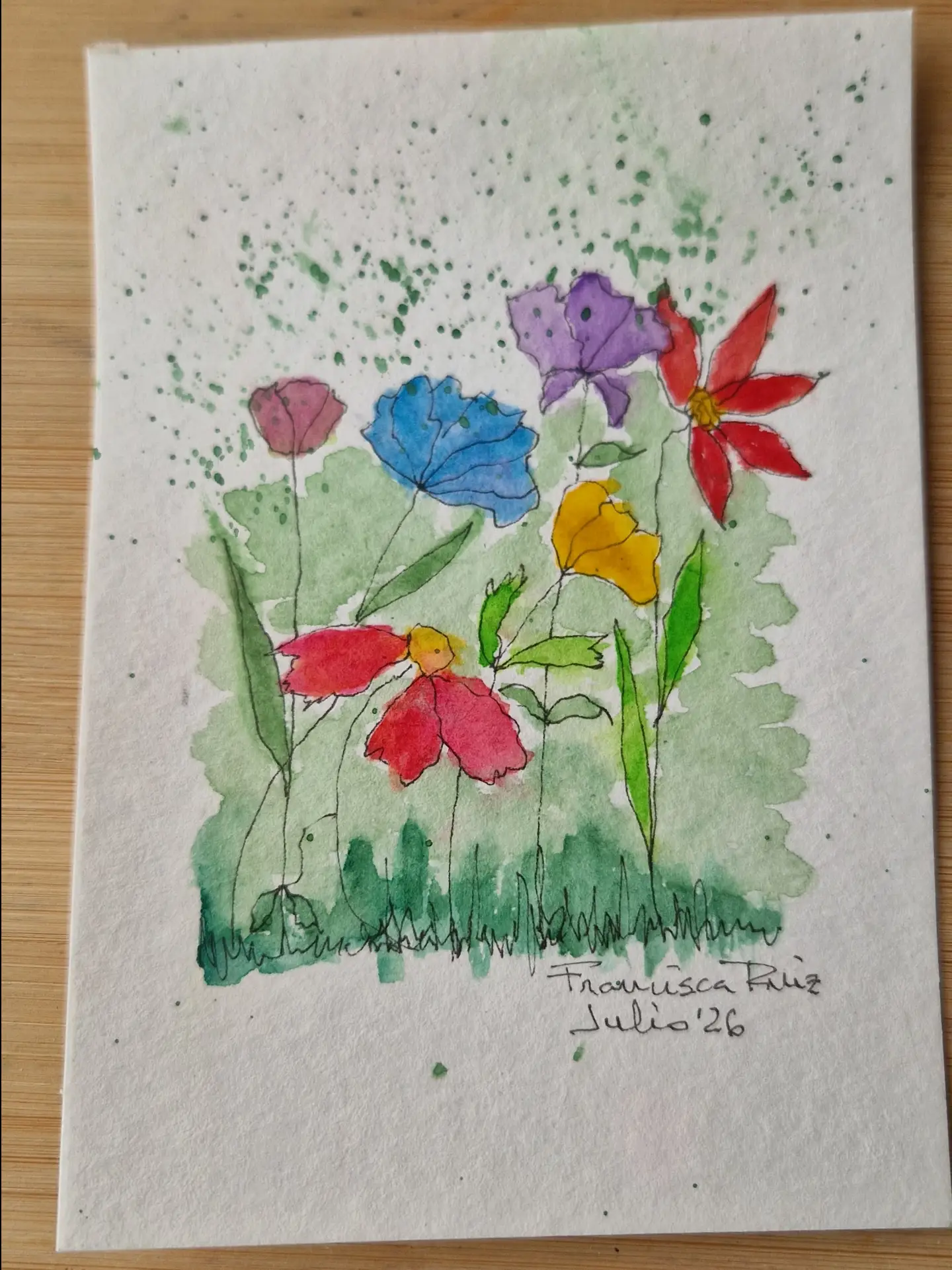 Acuarela vertical con flores rojas, azules, violetas, amarillas y rosas sobre una mancha verde.